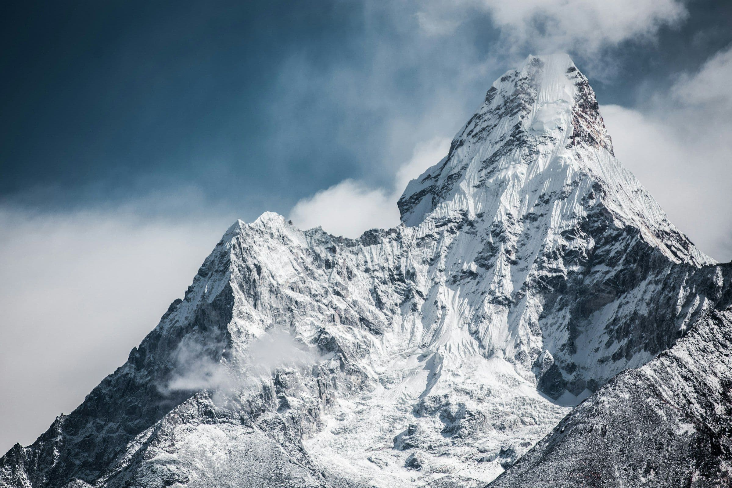 Snowbound summit of Ama Dablam in cold blue storm light
