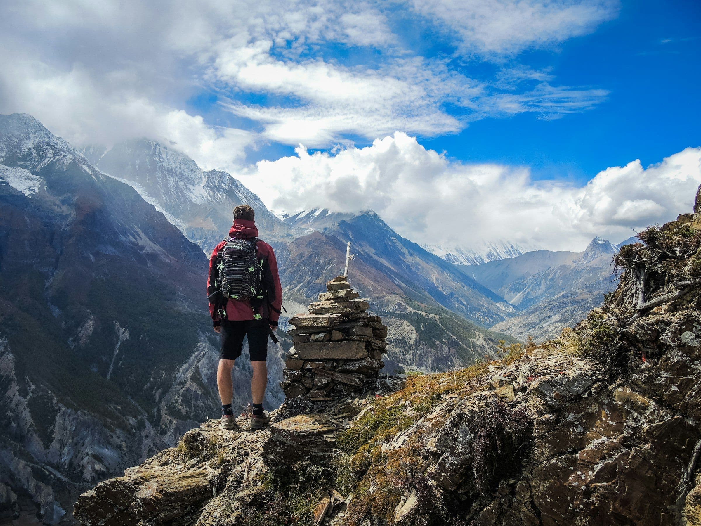 Trekker standing beside a stone cairn high above an Annapurna valley
