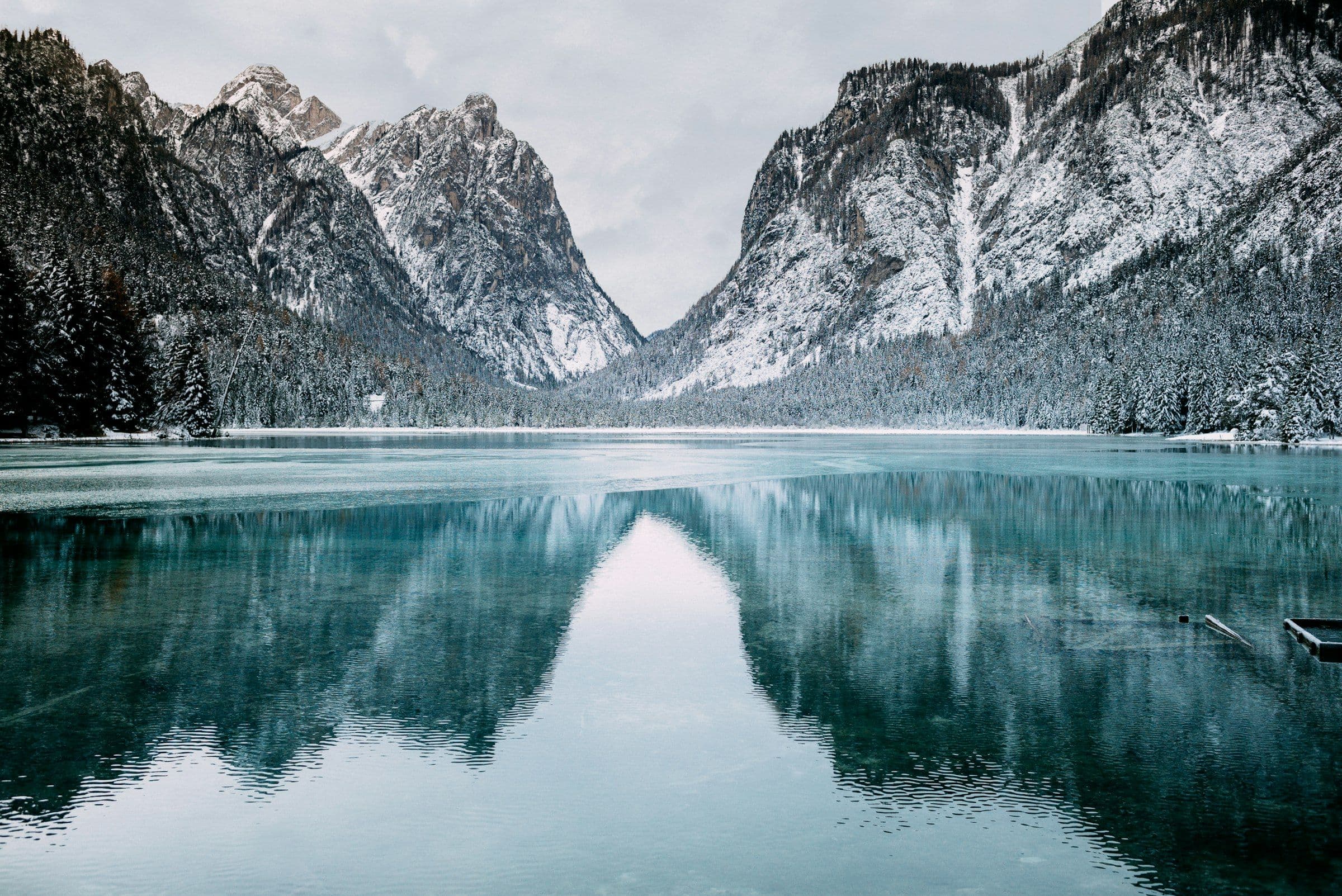 Still glacial lake reflecting snow-dusted cliffs