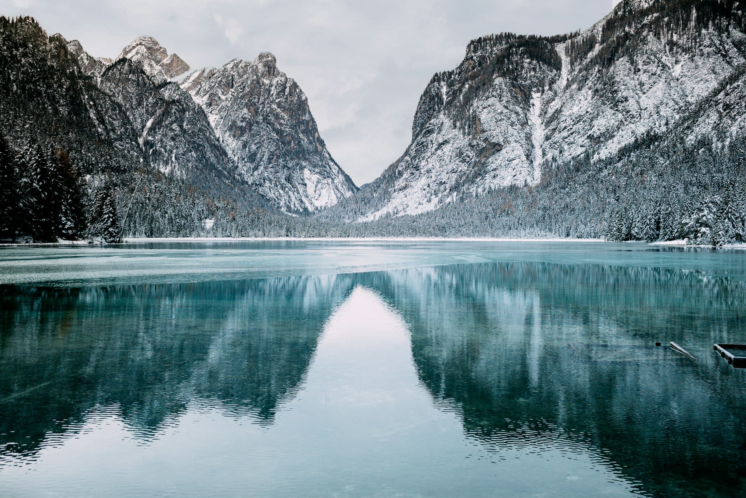 Still glacial lake reflecting snow-dusted cliffs