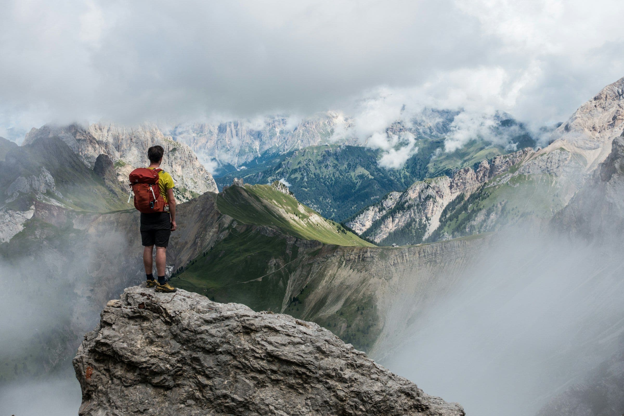 Trekker on a rock outcrop above a sea of mist and distant ranges