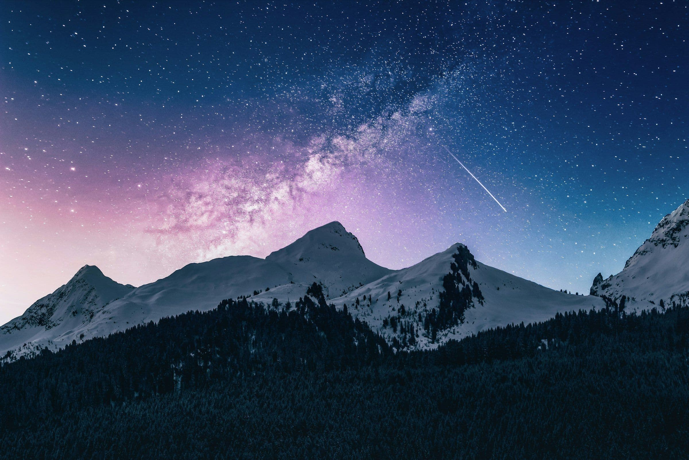 Snowbound peaks under a star-filled night sky
